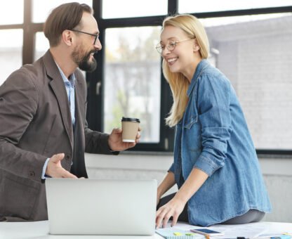 Happy businessman shows done project to his female partner, says that everything is okay, suggests to have coffee break. Two copywriters glad finish work, have great achievements, look in laptop